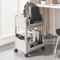 A rack backpacks, cart, movable bookshelf with wheels, small bookshelf, and a floor ceiling for storage next to the desk. 