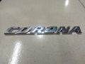 CORONA" chrome emblem, likely for a car. This is a car monogram or badge, commonly used on Toyota Corona vehicles.. 