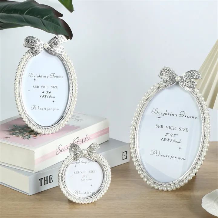 A bow shaped pearl studded diamond frame with a 3/6/7 inch oval photo ...