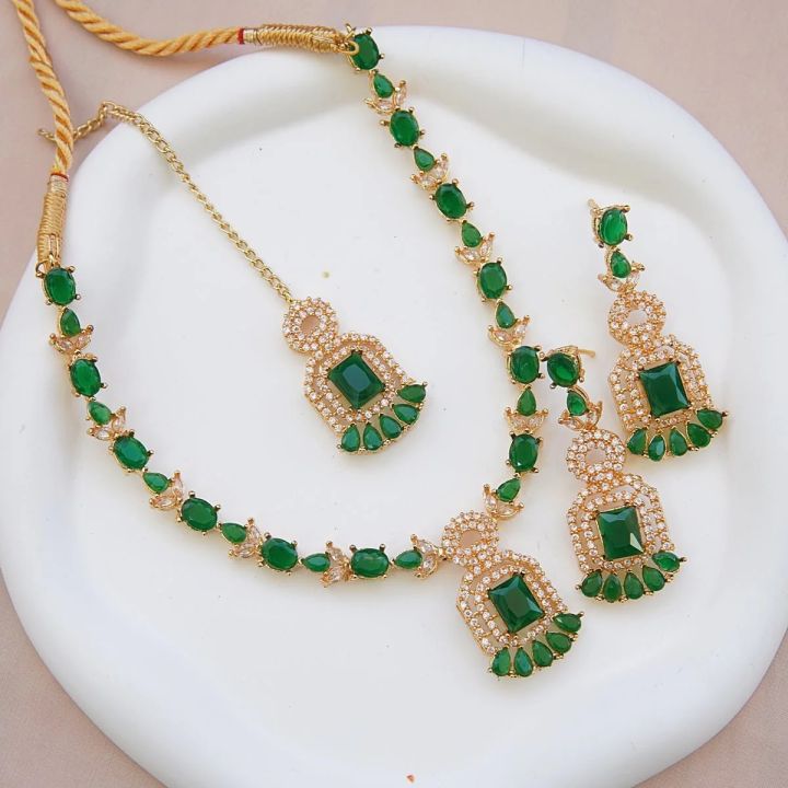 Necklace zircon jewellery set with earrings and maang tikka, all beautifully adorned with different colours stones that resemble emeralds or aquamarines.